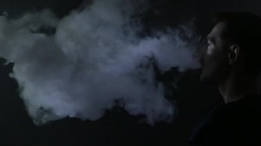 Bir kanepe ve vaping e-sigara üzerinde oturan bir adam. 4k Uhd