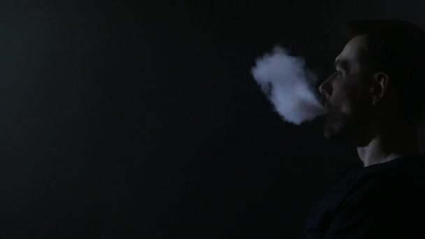 Un uomo seduto su un divano a vaporizzare sigarette elettroniche. 4K UHD — Video Stock