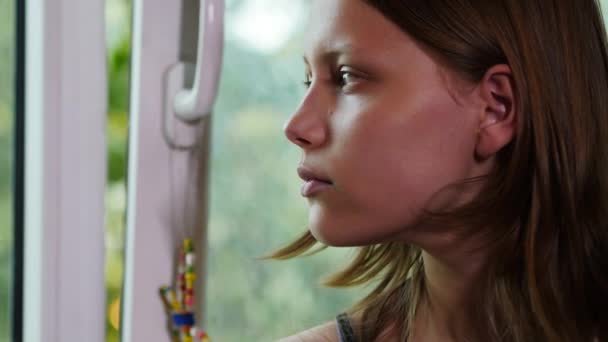 Cara de adolescente triste em uma janela. 4K UHD — Vídeo de Stock