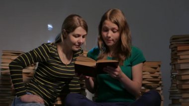 İki kız, anne ve genç kızı ya da iki kız kardeş kitap okuma ve kitap ile eğleniyor. 4k Uhd.