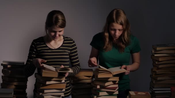 Zwei Mädchen, Mutter und ihre Teenager-Tochter oder zwei Schwestern lesen Bücher und haben Spaß mit Büchern. 4k uhd. — Stockvideo