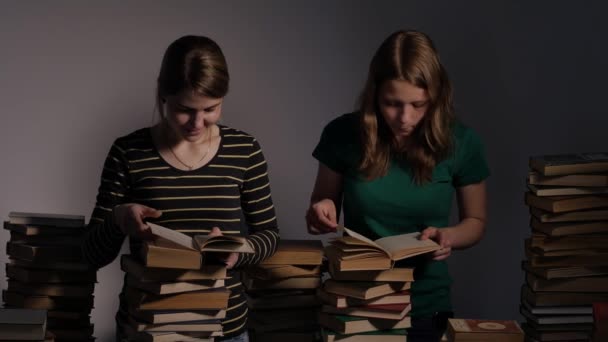 Duas meninas, mãe e sua filha adolescente, ou duas irmãs estão lendo livros e se divertindo com livros. 4K UHD . — Vídeo de Stock