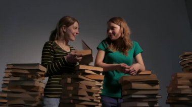 İki kız, anne ve genç kızı ya da iki kız kardeş kitap okuma ve kitap ile eğleniyor. 4k Uhd.