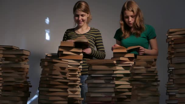 Dos niñas, su madre y su hija adolescente, o dos hermanas están leyendo libros y divirtiéndose con libros. 4K UHD . — Vídeo de stock