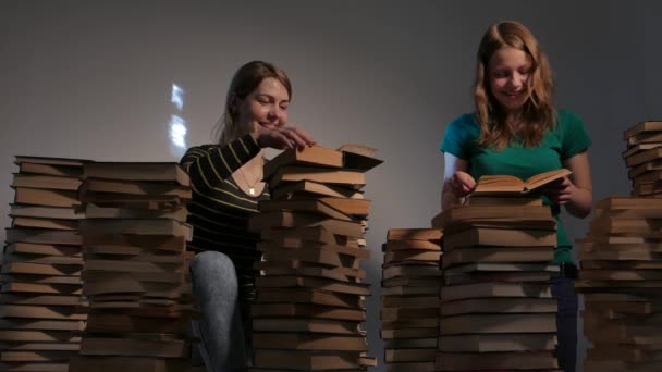 Duas meninas, mãe e sua filha adolescente, ou duas irmãs estão lendo livros e se divertindo com livros. 4K UHD . — Vídeo de Stock