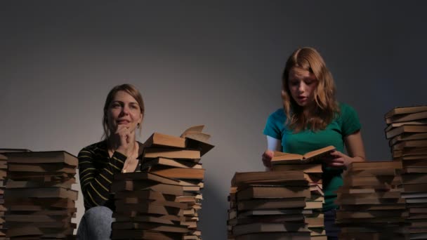 Duas meninas, mãe e sua filha adolescente, ou duas irmãs estão lendo livros e se divertindo com livros. 4K UHD . — Vídeo de Stock