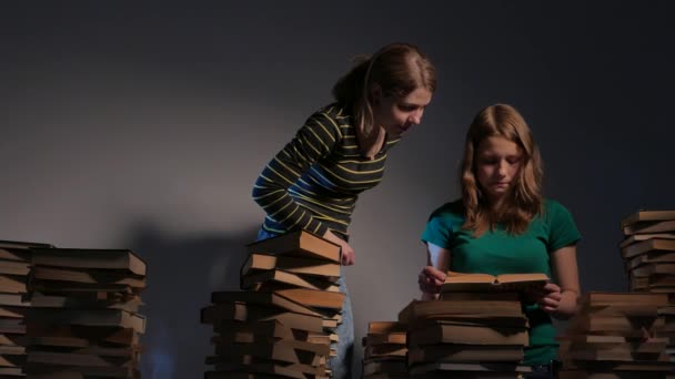 Zwei Mädchen, Mutter und ihre Teenager-Tochter oder zwei Schwestern lesen Bücher und haben Spaß mit Büchern. 4k uhd. — Stockvideo