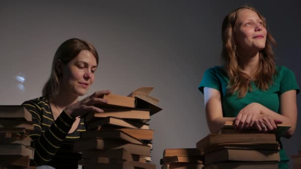 Dos niñas, su madre y su hija adolescente, o dos hermanas están leyendo libros y divirtiéndose con libros. 4K UHD . — Vídeo de stock