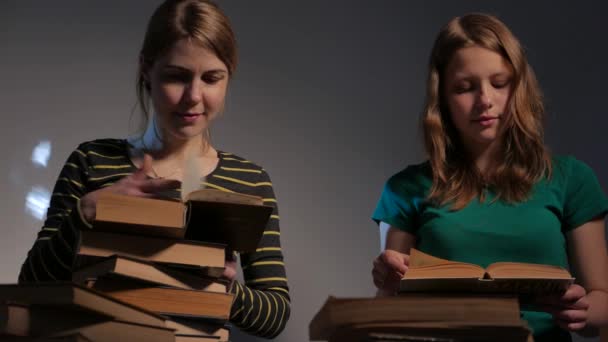 Duas meninas, mãe e sua filha adolescente, ou duas irmãs estão lendo livros e se divertindo com livros. 4K UHD . — Vídeo de Stock