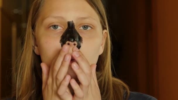 Gezichtsbehandeling. Tiener meisje reiniging van de poriën van haar neus met een modder masker. 4k Uhd. — Stockvideo