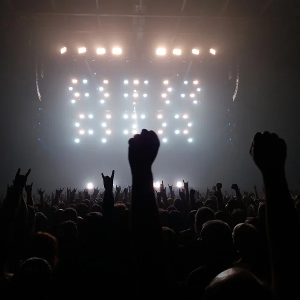 Publik med händerna upp på en rockkonsert Stockbild