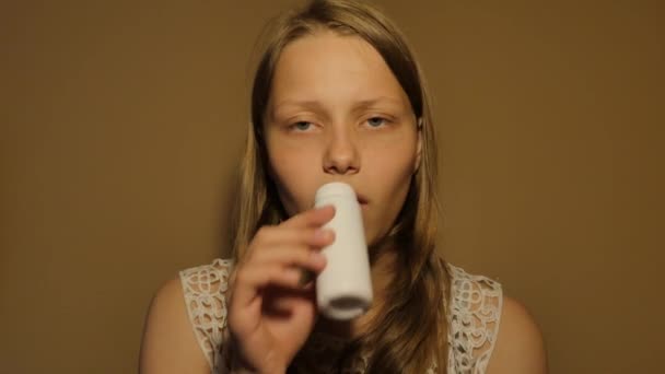 Дівчина-підліток п'є молоко або йогурт з маленької пляшки. 4K UHD — стокове відео