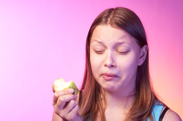Teen girl eating disgusting apple