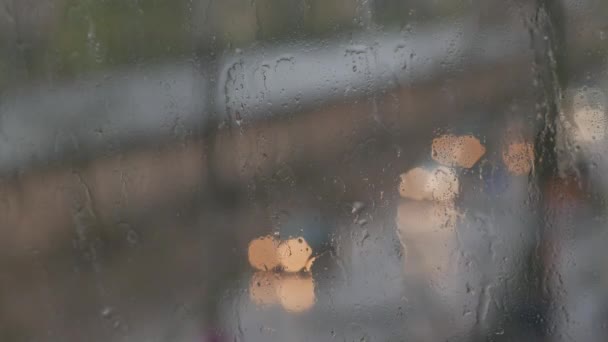 Абстрактные размытые огни и дождь падает через окно — стоковое видео