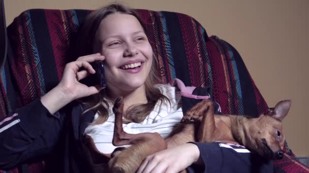 Teen girl talking by phone and holding little doggy — Stock Video