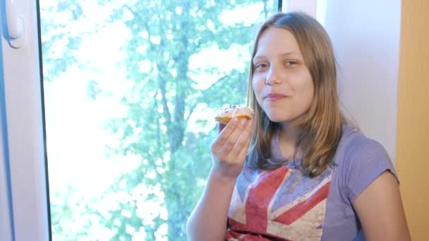 Девочка-подросток ест пончик — стоковое видео
