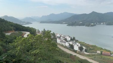 Virajlı yolu, gölü ve geleneksel köy mimarisi olan Guangxi manzarası.