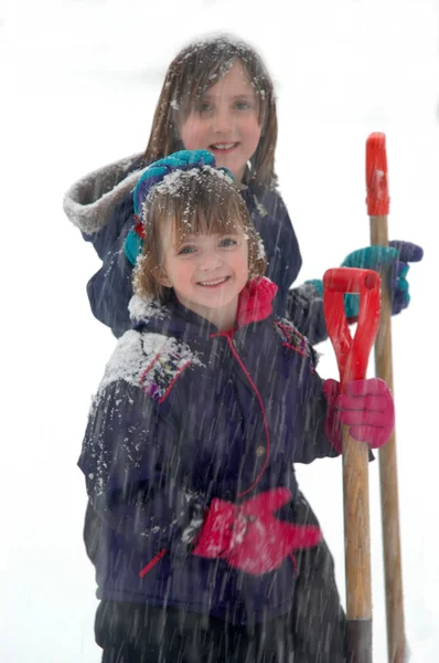 Joven chica paleando nieve en el día de invierno — Foto de Stock