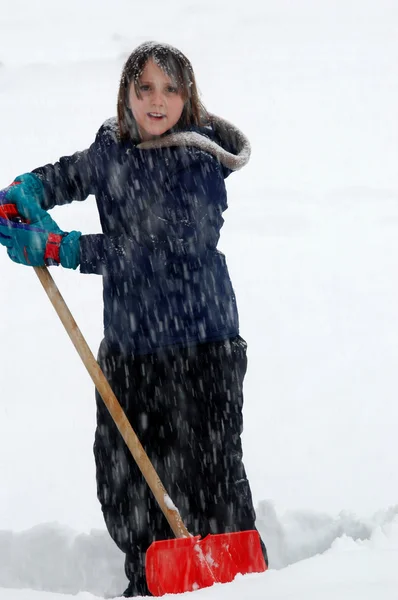 Joven chica paleando nieve en el día de invierno — Foto de Stock