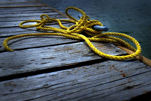Staré dřevěné Dock vodou žluté lano — Stock fotografie