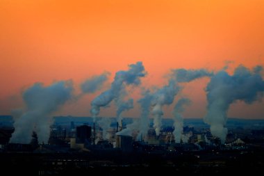 Factory smoke rising in air pollution at sunrise of sunset clipart