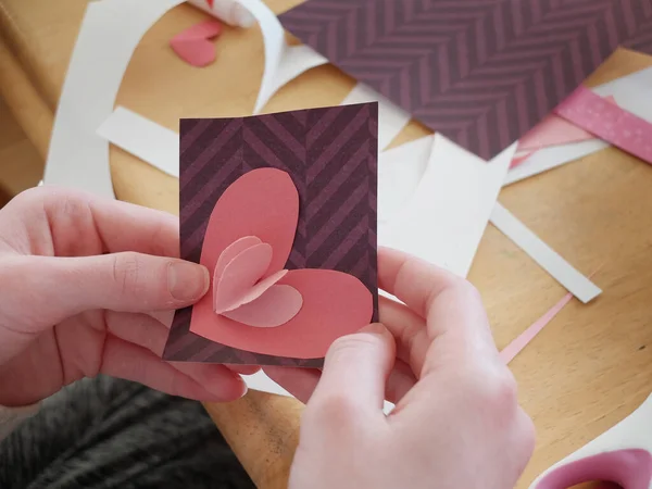 手を握り手作りのバレンタインハートカードを作る — ストック写真