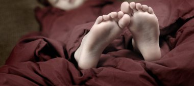 Ayakları kırmızı battaniyelerden fırlayan küçük bir kız.