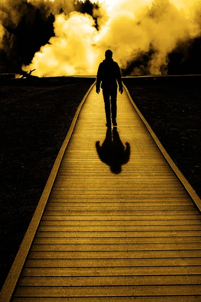 一个游客走在有蒸汽上升的木板路上的轮廓 — 图库照片