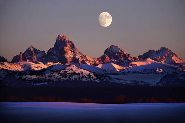 Sunset light with alpen glow on Tetons Tetons mountains rugged with moon rising