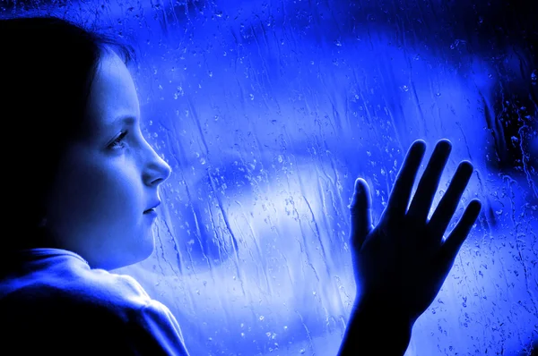 Dívka, vyhlíží smutný deštivý den okno — Stock fotografie