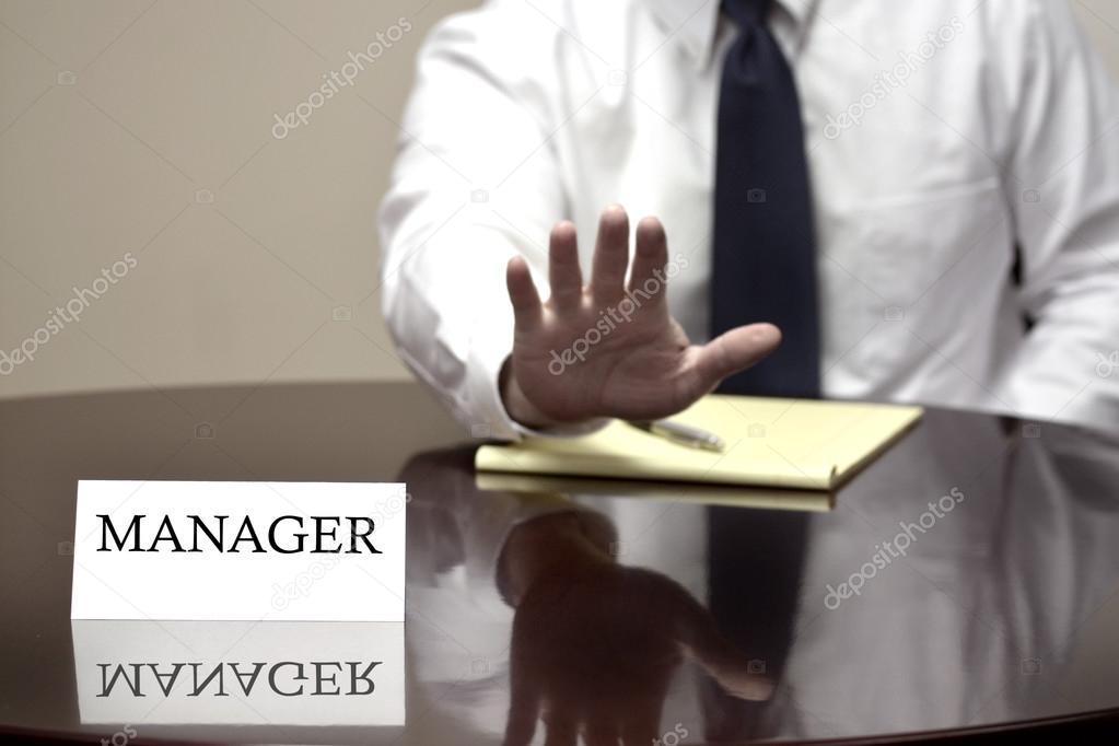 Manager At Desk Holding Hand up Stop Deal