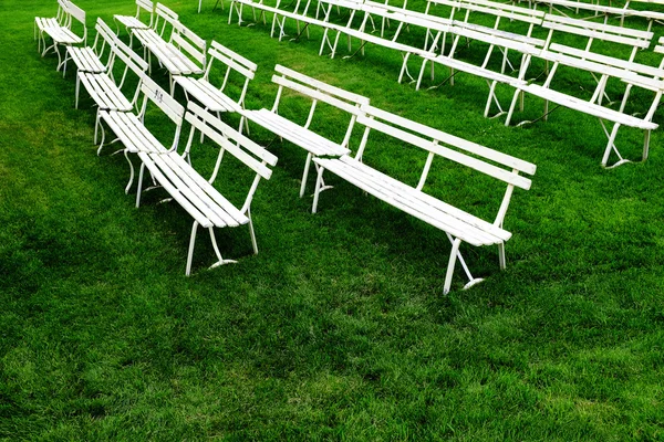 Linhas de bancos de parque branco para sentar-se na grama verde — Fotografia de Stock