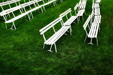 Yeşil çimenlerin üzerinde oturan için Beyaz Park banklar satırları