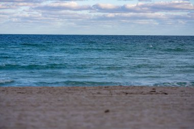 Sahilin fotoğrafı ön plandaki okyanus bulanık kumlara odaklanıyor.
