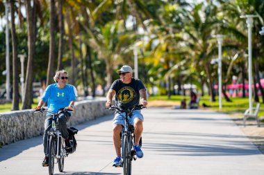 Miami Beach, FL, ABD - 7 Aralık 2020 Miami Beach Ocean Drive 'da bisiklet süren mutlu yetişkin adamlar