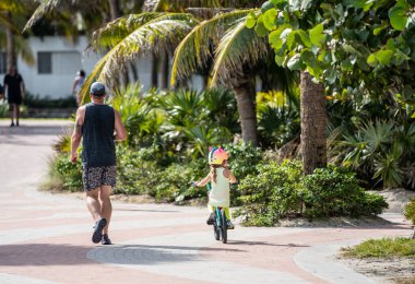 Miami Beach, FL, ABD - 7 Aralık 2020: Miami Beach Atlantic Greenway yolunda egzersiz yapan baba ve kız