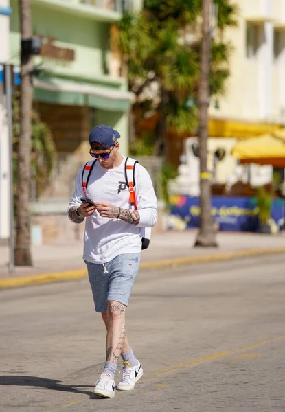 2021年1月30日 この電話を歩いて見下ろす男マイアミビーチ通りの写真 — ストック写真