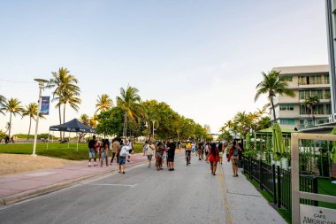 Miami Beach, FL, ABD - 26 Mart 2021: Polisin sokağa çıkma yasağı yaklaşırken Miami Beach 'te bahar tatili kalabalığı. Ocean Drive ve Lummus Park alanları