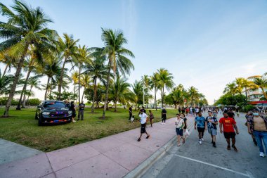 Miami Beach, FL, ABD - 26 Mart 2021: Polisin sokağa çıkma yasağı yaklaşırken Miami Beach 'te bahar tatili kalabalığı. Ocean Drive ve Lummus Park alanları