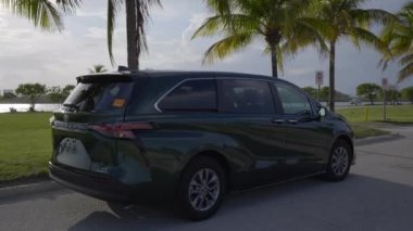 Miami, FL, ABD - 13 Mayıs 2021: 2021 civarında Toyota Sienna Melez Minibüs 'te palmiye ağaçları sahnesinde yürüyün