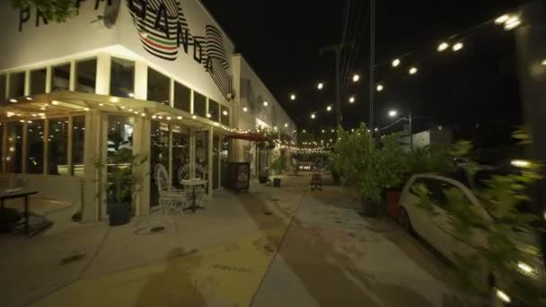 夜间穿过餐馆 头顶挂着灯光 — 图库视频影像