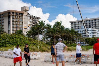 Miami Beach Surfside, FL, ABD - 26 Haziran 2021: Miami 'deki Champlain Kuleleri Surfside' ın yıkıldığı yeri ziyaret eden insanlar