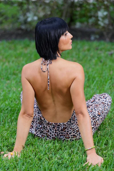 Mulher sentada na grama com as costas para a câmera — Fotografia de Stock