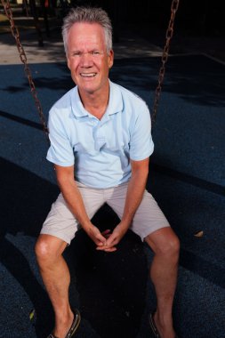Senior man sitting on a swing clipart