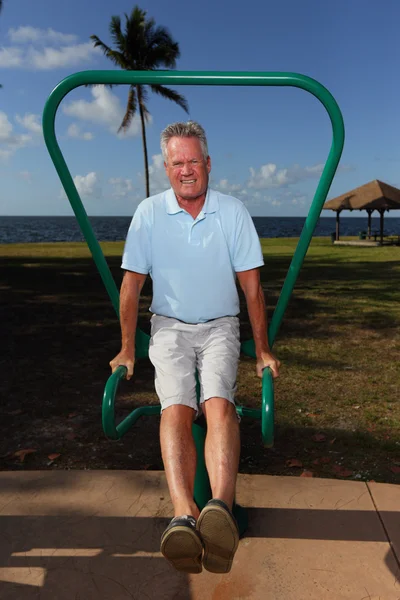 Senior man doing leg lifts in the park — Stock Photo, Image