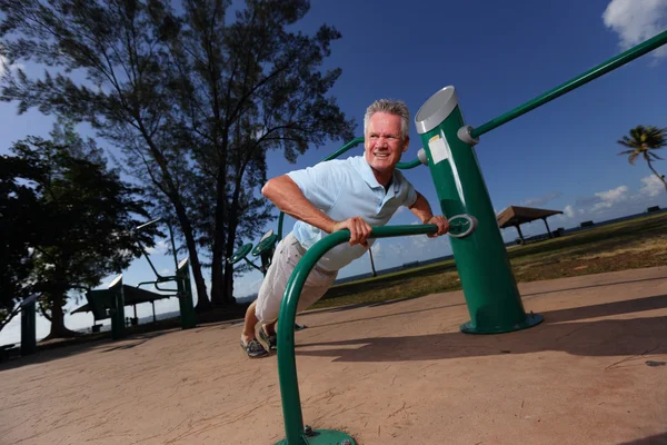 Sénior fazendo flexões no parque — Fotografia de Stock