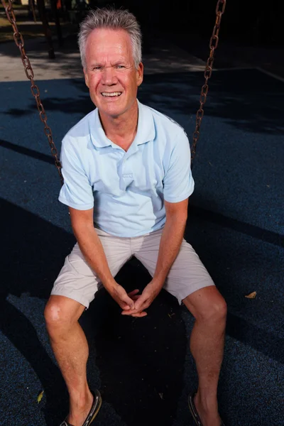 Senior sitzt auf einer Schaukel — Stockfoto