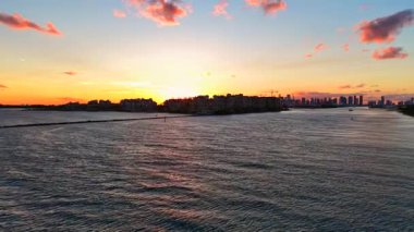 Fisher Adası ve Miami Limanı üzerinde doymuş canlı Miami Sahili gün batımı. Hava aracının yükselişi 2025 4k 24 peni gösteriyor.
