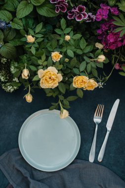 Çiçek desenli bir tatil masası. Tabakta gümüş çatal bıçak var.