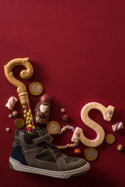 Holiday background Saint Nicholas, Sinterklaas, children's shoe with chocolate, nuts, gifts and sweets